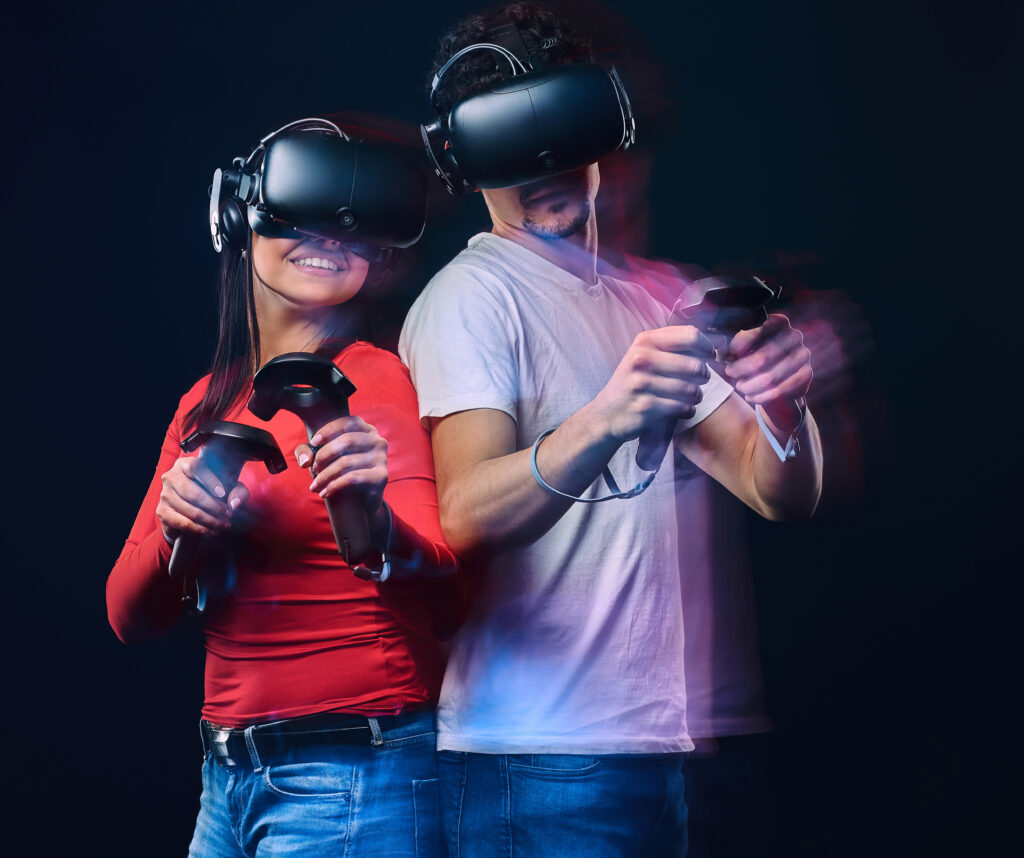 Happy Friends Playing Video Games Wearing Virtual Reality Glasses With Controllers Isolated Dark Background Photo With Light Effect 1024x858